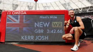 Josh Kerr poses beside scoreboard after setting men's mile world record