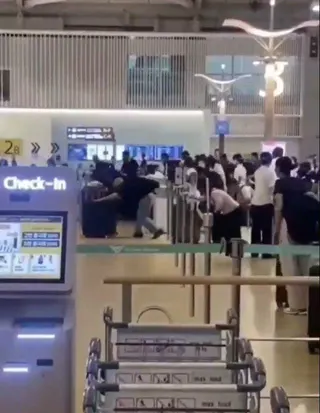 部分旅客未按排隊路線移動，彎身帶著行李箱衝向櫃台。 （視頻截圖）
