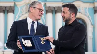 Starmer holds a medal Zelensky gives him as they speak to each other