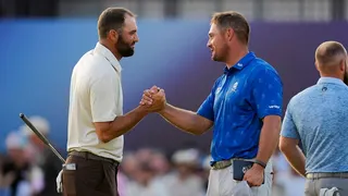 Bryson DeChambeau shakes hands with Scottie Scheffler on the 18th hole.