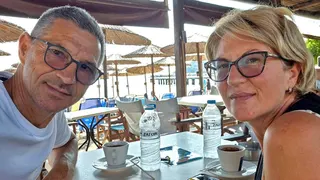 Karovic Ljubisa and his wife Svetlana Grković, smiling for a photo in a bar which appears to be at a holiday resort