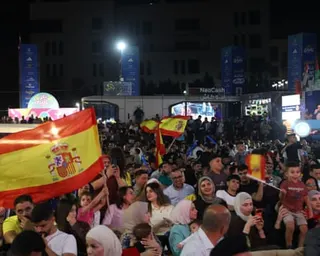 Supporters waving Spanish flags follow the match with excitement.