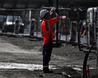 A worker drinks water from a bottle at a construction site