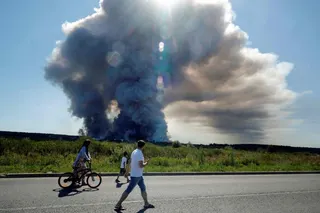 Residents walk past the smoke rising from Wildberries logistics complexes in the town of Elektrostal outside Moscow on Saturday. Photo: AFP