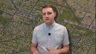 Chris Spargo stands in front of an isometric view of a city in SimCity 4