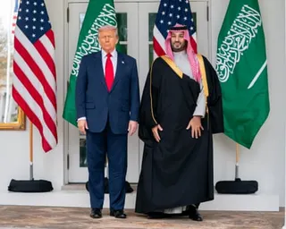 Donald Trump and Mohammed bin Salman stand side by side between American and Saudi Arabian flags