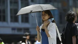 A woman walking on the street shields herself with a parasol on June 17, 2025, in Tokyo, Japan.