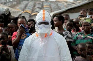 A health worker stands next to displaced people waiting for the burial of suspected Ebola victims at a displaced persons camp in Bunia, Congo, last month. Photo: Reuters