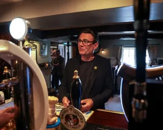 Andy Burnham stands at the bar in a pub during the Makerfield by-election campaign