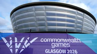 A futuristic silver arena with a purple Commonwealth Games Glasgow 2026 banner in the foreground
