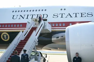 Trump waves from the top of the stairs at the door of Air Force One.