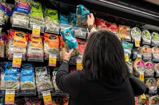 a woman selects bagged salad at a supermarket
