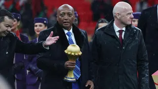 Caf president Patrice Motsepe, centre and dressed in a long black coat and white shirt and blue tie, carries the Africa Cup of Nations trophy in his right hand as he walks flanked by Fifa president Gianni Infantino.