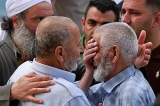 Men comfort one another as they mourn outside a hospital