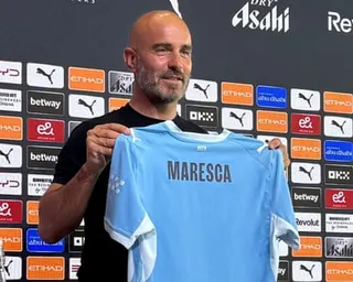Enzo Maresca holds a Manchester City shirt with his name on at his first press conference as the club's manager on Friday