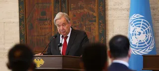 联合国秘书长安东尼奥·古特雷斯在会议讲台上发表讲话，背景中可以看到联合国旗帜。