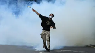A protester throws back a tear gas canister toward police as supporters of the Cockroach Janta Party march on parliament on the opening day of its monsoon session, demanding the resignation of Education Minister Dharmendra Pradhan over exam paper leaks, in New Delhi, India, 20 July, 2026.