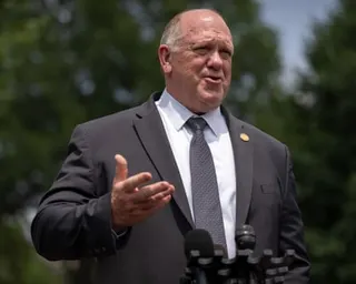 man gestures while speaking at outdoor microphones