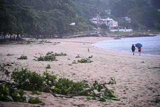 People walk on a beach with debris from Typhoon Noul which passed close to Hong Kong July 26, 2026. A flash flood caused by heavy rain struck a tourist site in north-west China today, killing 10 people and injuring 23 while large swaths of southern China are on high alert for floods today after Typhoon Noul made landfall early in the morning. — AFP pic