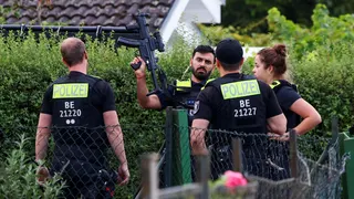Four police officers are pictured, with one officers holding a gun up
