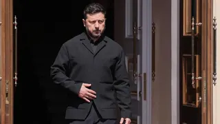 Zelensky, wearing a dark suit, walking through a doorway