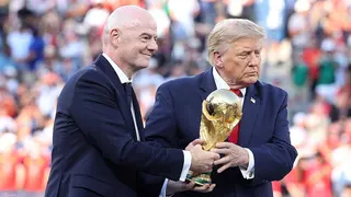 Gianni Infantino (left), wearing a dark suit and tie, and Donald Trump (right), wearing a dark suit and red tie, holding the gold World Cup trophy