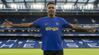 Morgan Rogers stands with his arms outstretched after joining Chelsea