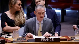 France's UN Ambassador Jerome Bonnafont speaking at the UN Security Council on the table with a "France" placard while two people sit behind him