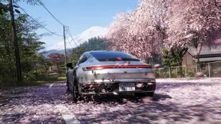 Forza Horizon 6 official image showing a Porsche driving away towards distant Mt Fuji, with the road and nearby trees covered in pink cherry blossom