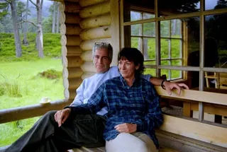 man and woman sit together on a wooden bench on a log cabin porch in a green, wooded area
