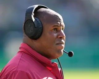 Eric Bieniemy wears a headset on the sideline during an NFL game.