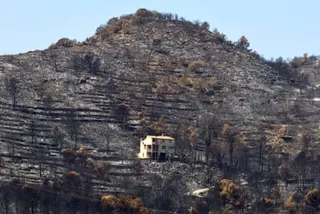 A house sits on the scorched slope of a tall hill