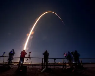 people watch the bright trail of a rocket launching into space