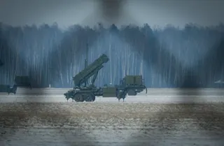 A Patriot missile launcher system stands in a snowy field with misty forest in the background