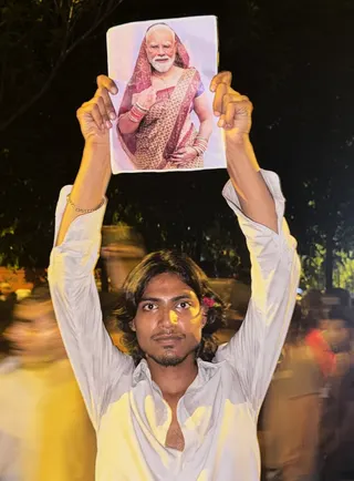 A protester holds a placard with a portrait of Prime Minister Narendra Modi in a sari in New Delhi on July 23. Photo: AP