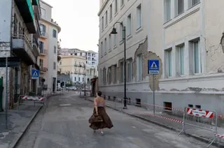 A woman walking through a closed street with damaged buildings