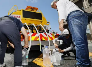 People collect water from a tanker truck in Uki, Kumamoto prefecture, on Friday. Photo: Kyodo
