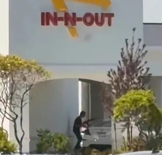 A person with a gun outside an In-N-Out Burger restaurant