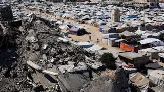 Palestinos caminan entre los escombros de edificios residenciales destruidos durante la ofensiva israelí, mientras los desplazados se refugian en tiendas de campaña, en la ciudad de Gaza, 4 de julio de 2026.