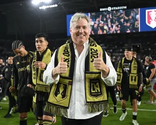LAFC Co-Managing Owner Larry Berg gives two thumbs up while wearing a yellow and black scarf at a stadium