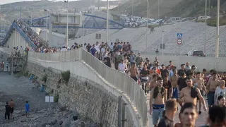 Dozens of migrants walking on a coastal path