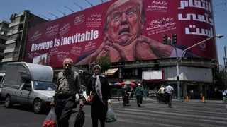 Peatones caminan frente a una valla publicitaria que muestra al presidente de Estados Unidos, Donald Trump, siendo sujetado por el cuello junto al mensaje "La venganza es inevitable", en inglés y farsi, en Teherán, Irán, el lunes 27 de julio de 2026.