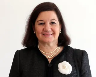 a woman wearing black with a pearl necklace