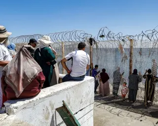 A crowd of waiting people watch across the border fence at at Morocco's Bab Sebta crossing to Ceuta