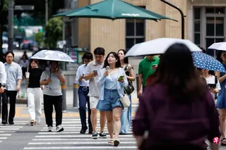 面对极端高温天气，韩国首尔街头出门撑伞遮阳的人多了。 （彭博社）