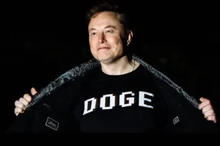 Elon Musk wearing a T-shirt with the word "DOGE" printed on the front.