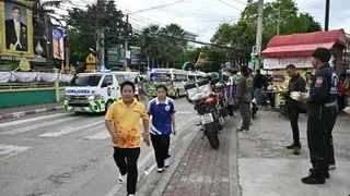 泰国首都曼谷以北的暖武里府邦桂县一所学校发生枪击事件，校外停了多辆救护车，学生快步离开。（图取自法新社）
