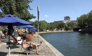 巴黎塞納河畔在夏季布置成沙灘度假風，有躺椅及遮陽傘，但人們享受日光浴，悠閒地度過...