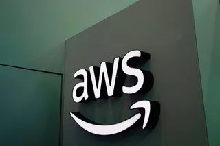 Photo of an Amazon logo hanging on a green wall that reads “AWS.”