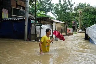 A man walks through floodwater caused at Bagong Silagan village in Quezon City, Metro Manila, Philippines. Photo: AP